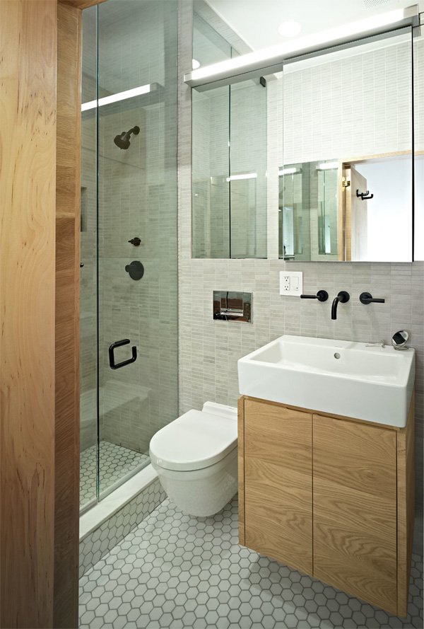 Salle de bain avec de grands miroirs, des murs et un sol en gris et des meubles en bois naturel.