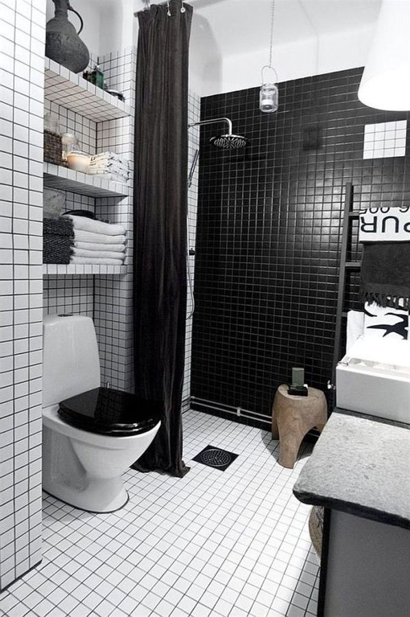 Pared posterior de la ducha en azulejitos pequeños negros, resto del baño blanco, cortina de ducha negra