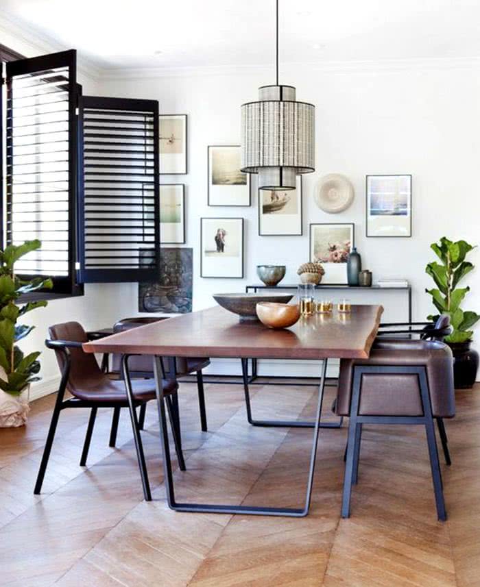 mesa de comedor y sillas de madera y metal negro, paredes con cuadros, lámpara colgante sobre la mesa