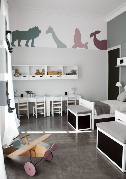 pared gris con dibujos de animales, estantes blancos, mesas blancas