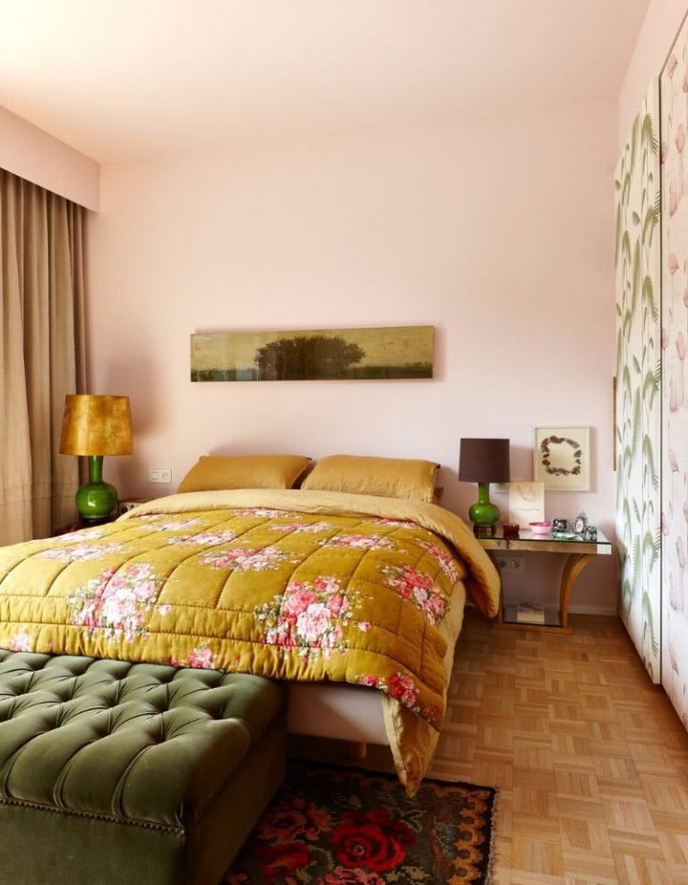 cama con acolchado tonos mostaza y beige, paredes rosa pastel, asiento capitoneado en verde oliva