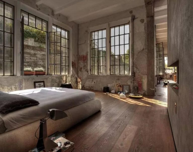dormitorio industrial con paredes de cemento y ladrillo añejadas, suelos en madera, cama baja
