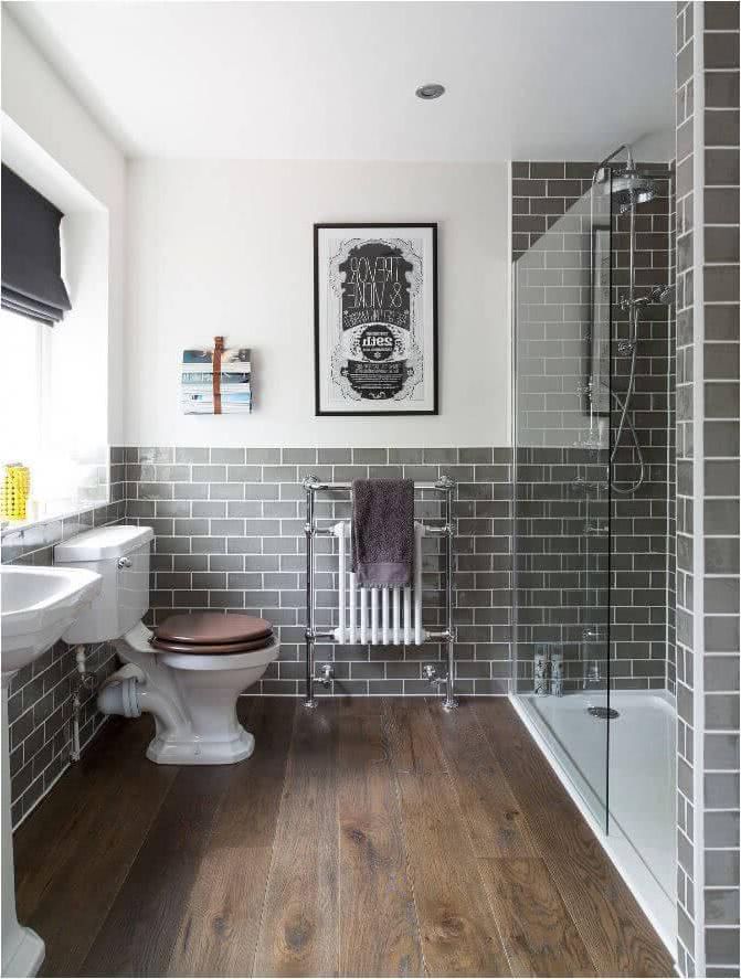 Baño pequeño con ducha con mampara de cristal, azulejos de metro en color gris, suelos en madera