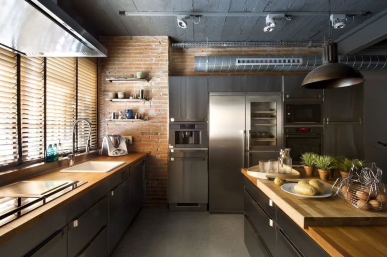 cocina con paredes de ladrillo visto, encimeras en madera, electrodomésticos de acero inoxidable