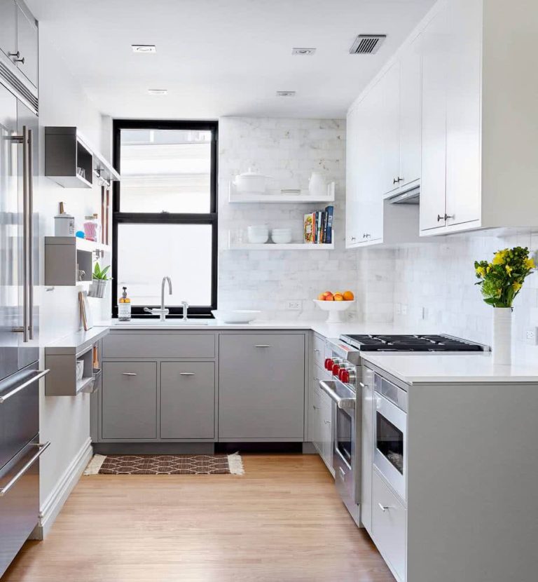cocina con armarios bajos de color gris, armarios altos blancos, paredes con azulejos en vetas blancas y grises