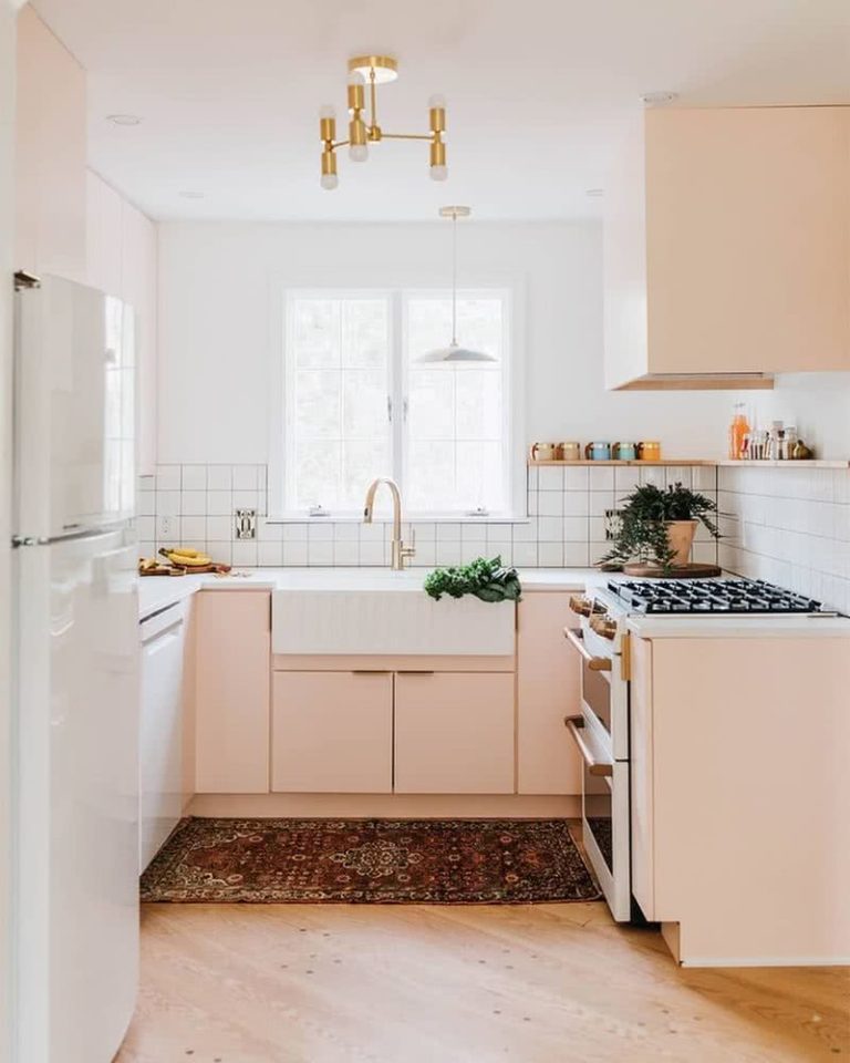 cocina compuesta por paredes y azulejos blancos, armarios en rosa coral pastel