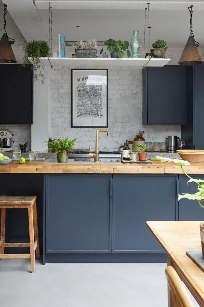 cocina azul grisácea con encimera en madera y paredes blancas