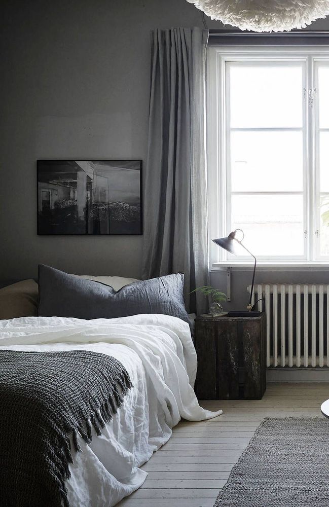 dormitorio con paredes grises, cama en gris y blanco, suelo de madera pintada en gris pálido