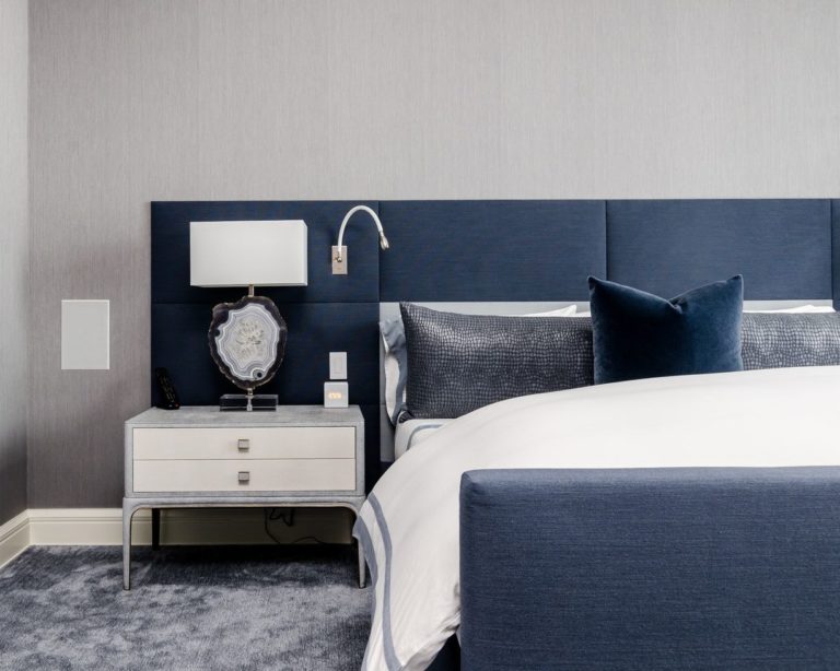 cama con cabecera grande acolchonada en azul oscuro, cama con cojines grises y azules, pared gris