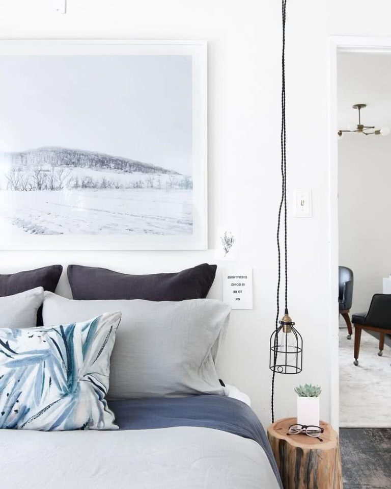 habitación con paredes blancas, cama decorada con sábanas grises y azules