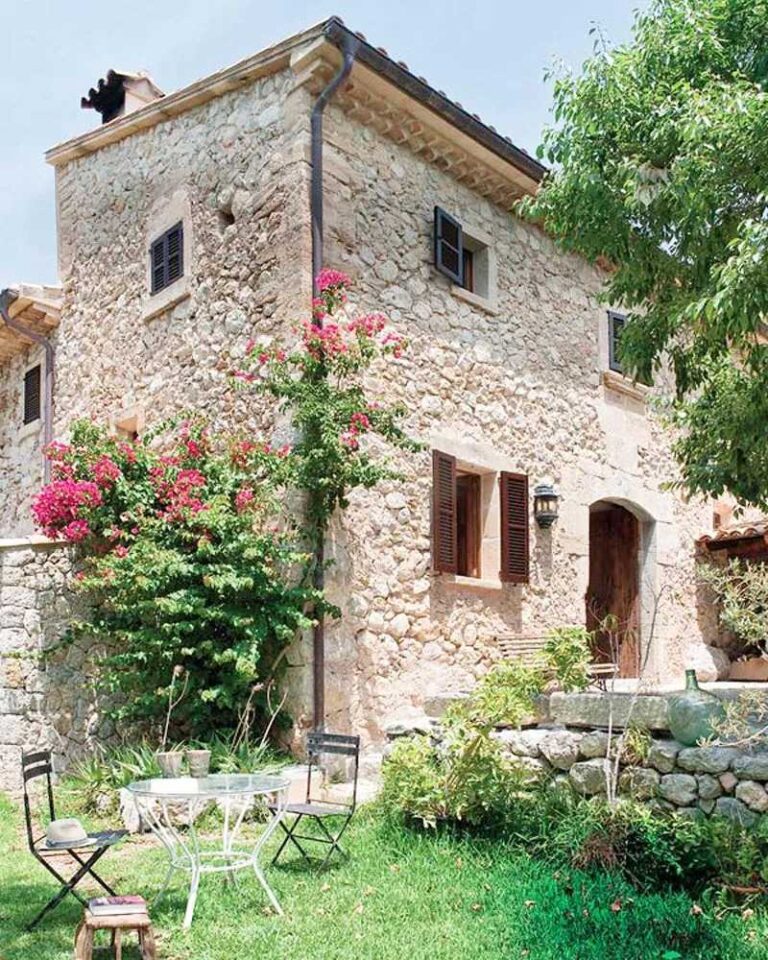 casa de campo con paredes de piedra y pequeño jardín