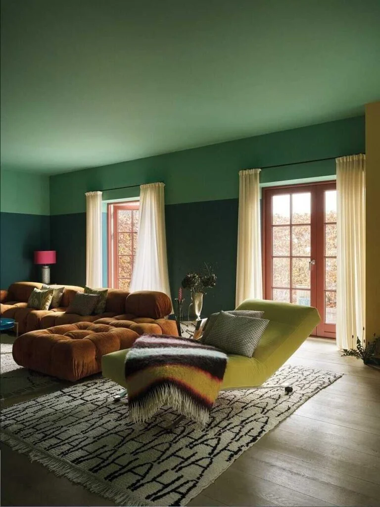 Sala con paredes y techo verde oscuro, sofá capitoneado terracota, sillón reclinable verde Lima