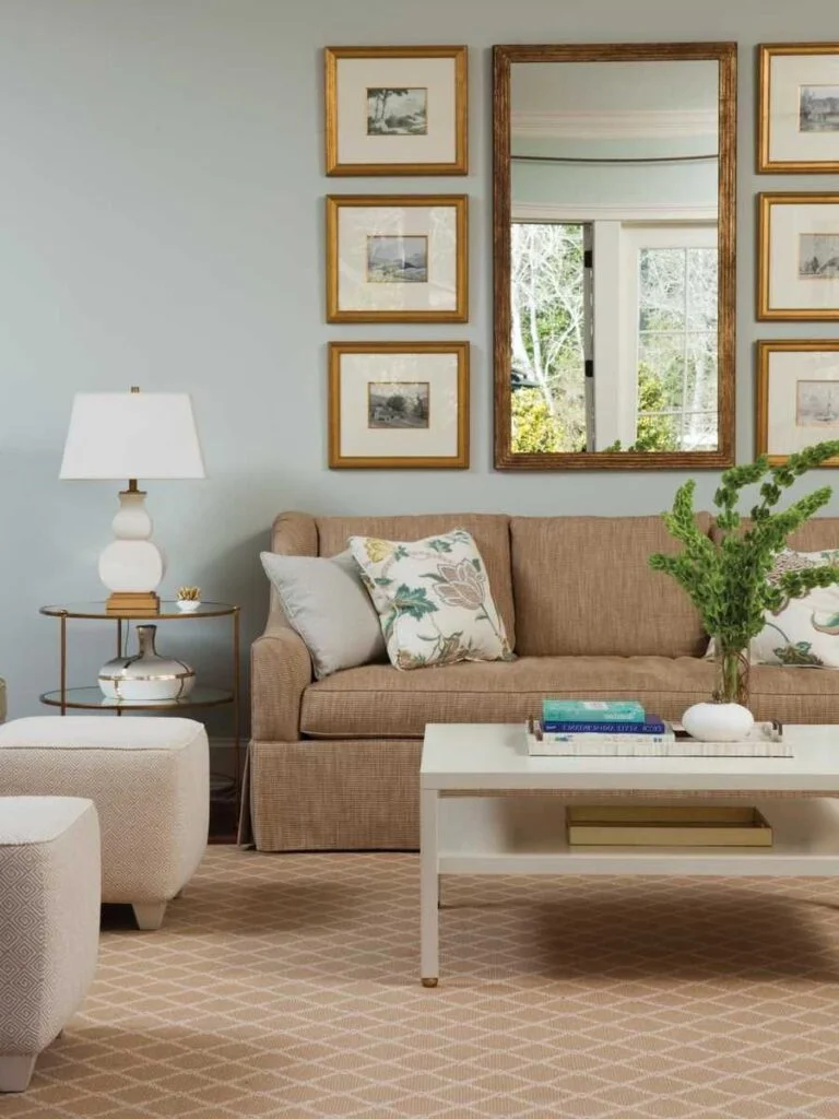 Salón con pared celeste grisáceo, sillón beige rústico, mesa de centro blanca, espejo en la pared