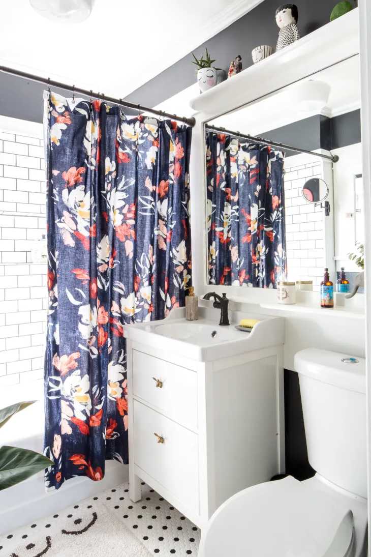 Ducha con cortina estampada con flores en todos los azules, rojos y blancos, lavabo con mueble e inodoro blancos